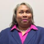 Professional headshot of Empish wearing a navy blue blazer and fuchsia blouse