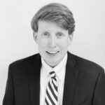 Headshot of man smiling with black and white suit on