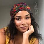 Woman with black hair, head covering, and yellow top