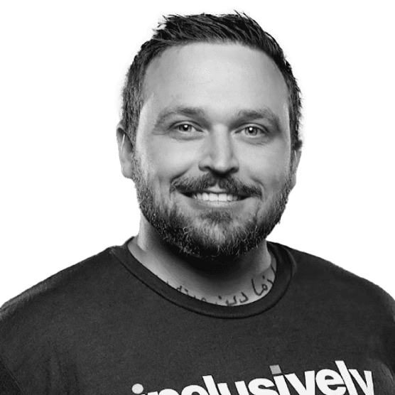 Professional headshot of a smiling man with brown hair and a beard in a striped sweater.